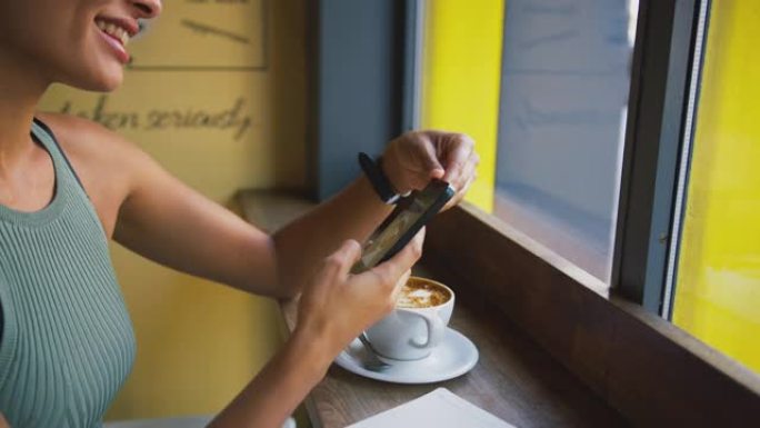 女性顾客在咖啡店橱窗里用手机短信