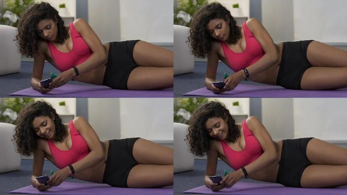 满意的混血儿女性在智能手机上检查失重结果，健身