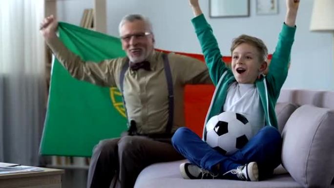 爷爷和孙子看足球，挥舞葡萄牙国旗，为胜利而高兴