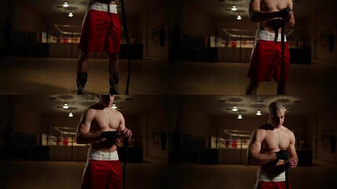 在健身房里，一个穿着拳击靴和短裤的男子在拳击戒指的背景下，手上缠着绷带。