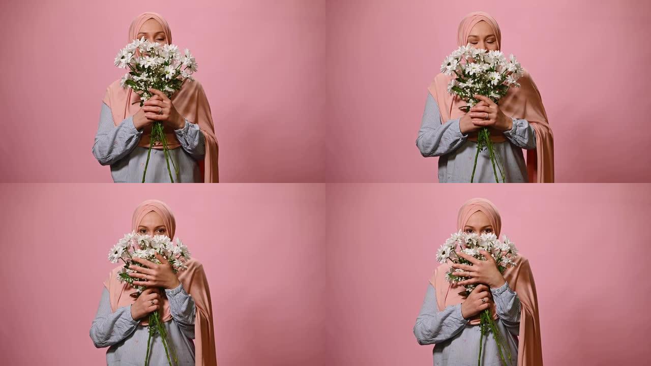 华丽的穆斯林妇女头部覆盖着粉红色的头巾，享受春天的花香