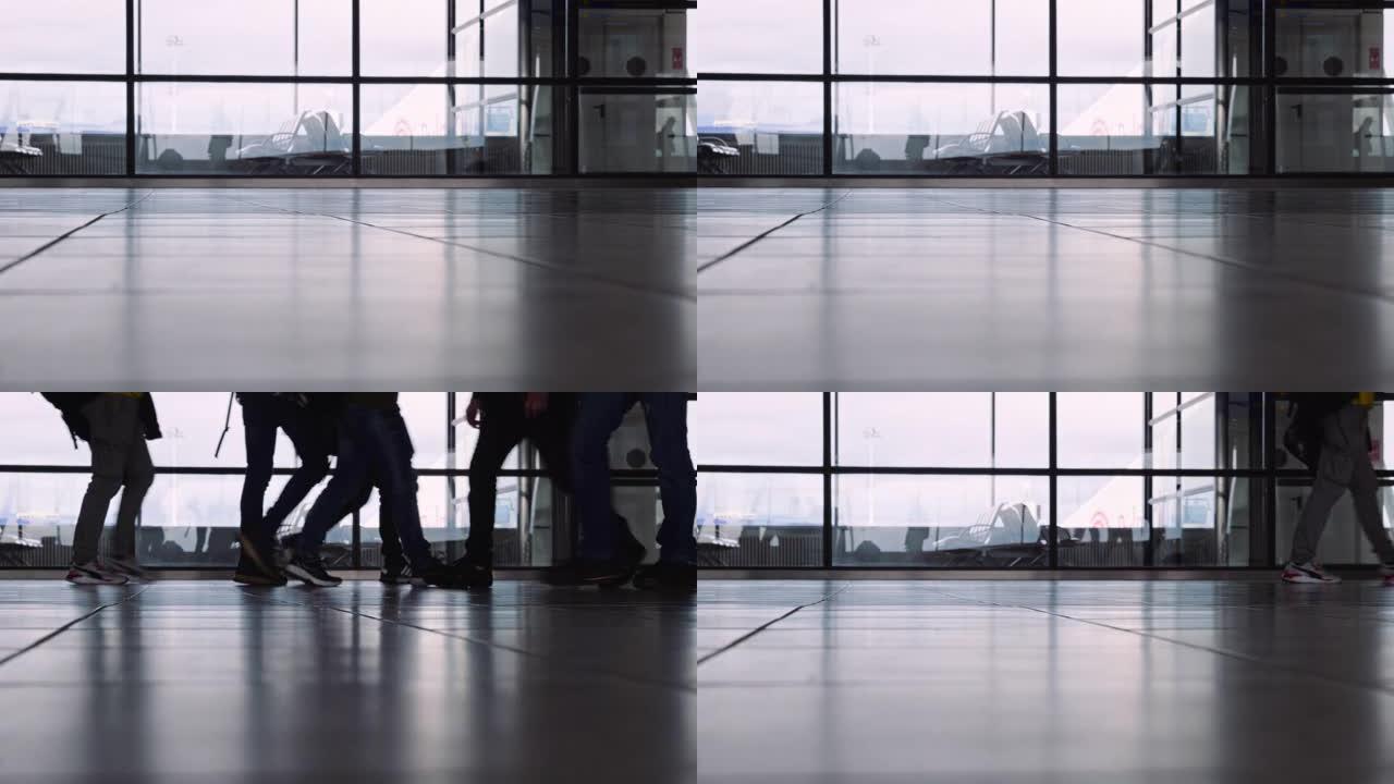 人们在机场航站楼快速行走，低角度视角。背景下的户外飞机。