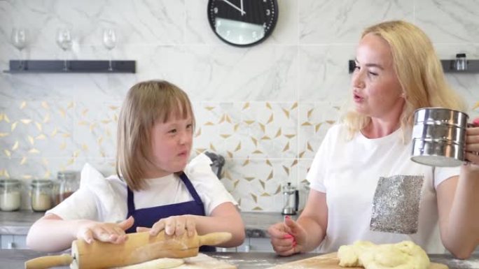 患有唐氏综合症的女孩和她迷人的母亲，在厨房里烤面团馅饼。国际唐氏综合症日概念。