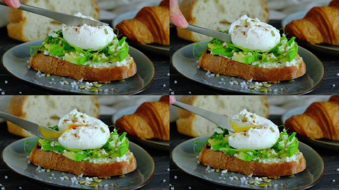 鳄梨三明治配荷包蛋。特写侧视视频，用刀切一个带流鼻涕的蛋黄的荷包蛋，4k高质量镜头