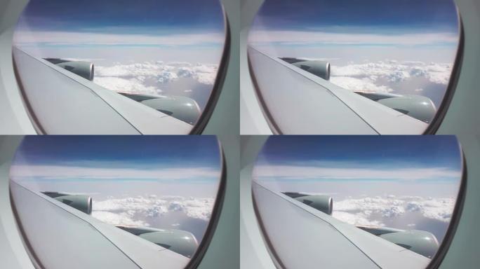 晴天，大型飞机飞越云层。从乘客窗到机翼和两个引擎的视图