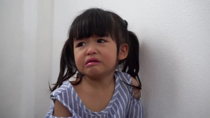 一个乱扔垃圾的亚洲女孩坐在康纳房间里，在被停电惩罚后哭泣。