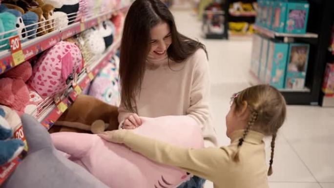 母亲在儿童百货公司向女儿展示大毛绒玩具，两人都微笑着