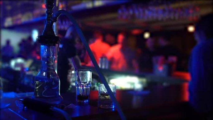 水烟和两个玻璃杯站在夜总会的吧台上，派对气氛