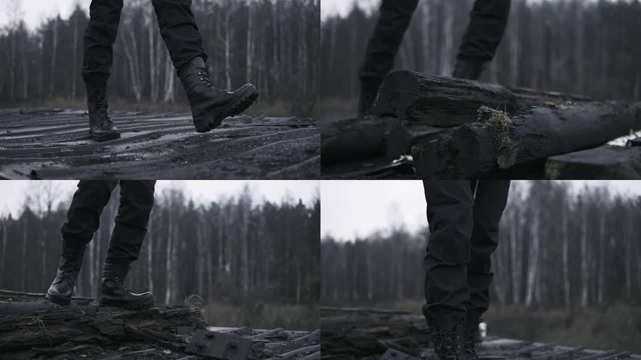军靴中的特写腿在空旷的森林中踩在火车站生锈的马车上