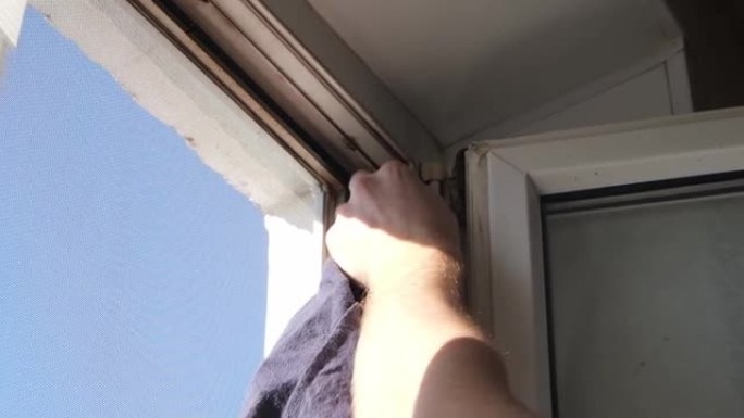 男子用脱脂剂擦拭窗框，并在其上粘上密封橡胶带以绝缘噪音