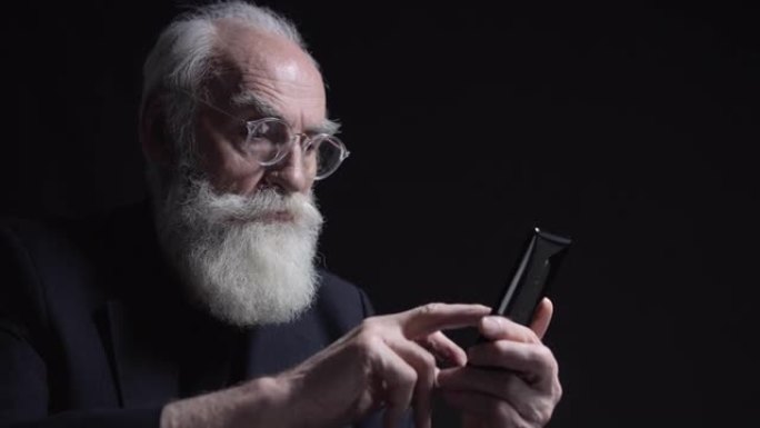 老人戴着眼镜，留着长长的灰色胡须，关闭智能手机上的应用程序