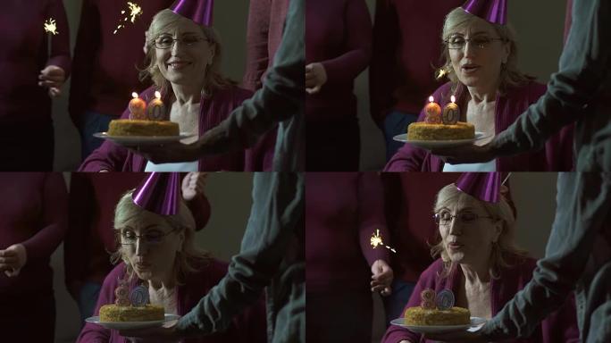 高级妇女在蛋糕上吹蜡烛并微笑，庆祝80岁生日