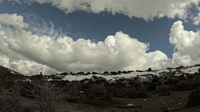延时视频显示云层在积雪覆盖的岩石山上掠过。