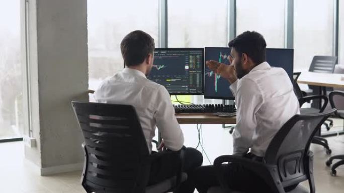 两名交易员坐在办公室的桌子前，一起监控股票数据，蜡烛图，屏幕上的资金流动，集中团队合作，讨论战略概念