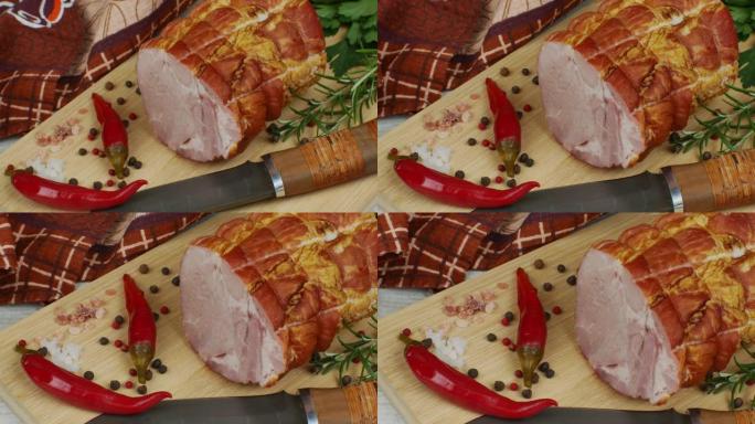 一块多汁可口的猪肉培根放在木菜板上，配有雕刻刀、多色多香果、红辣椒、欧芹、莳萝和罗勒。肉制品的概念