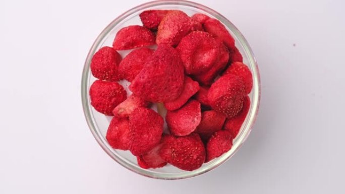 冻干草莓，是一种经过加工的水果，保留了食物的营养价值。在白色背景上隔离的玻璃碗中冻干草莓。