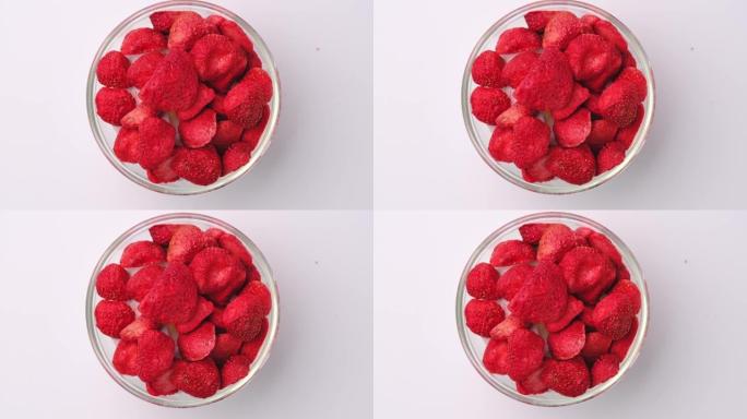 冻干草莓，是一种经过加工的水果，保留了食物的营养价值。在白色背景上隔离的玻璃碗中冻干草莓。
