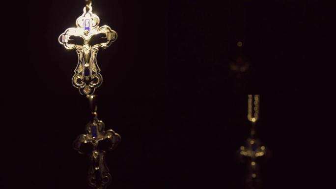 铁链上有耶稣基督的金色十字架从黑暗中出现
