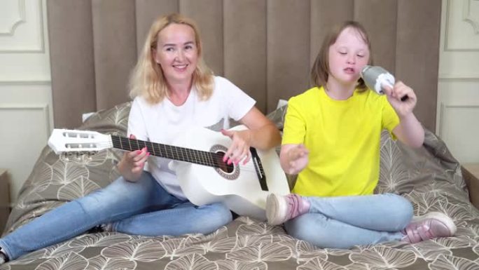 一个十几岁的女孩和她的母亲在家里穿着配套的衬衫弹吉他。家庭外观。国际唐氏综合症日概念。