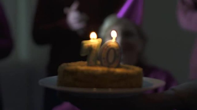 70岁快乐的老妇人在家庭聚会上吹生日蛋糕上的蜡烛