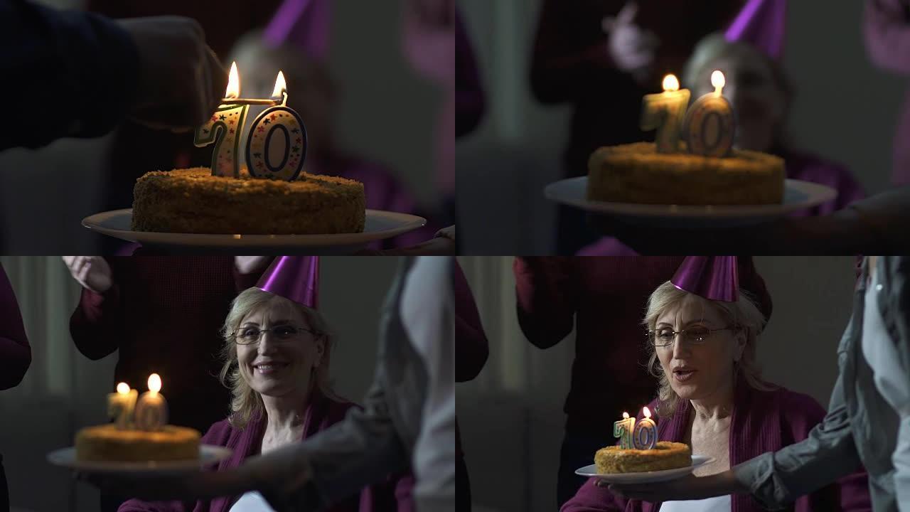 70岁快乐的老妇人在家庭聚会上吹生日蛋糕上的蜡烛