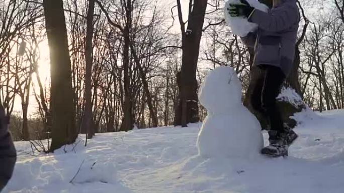 男孩在慢动作的冬季公园堆雪人