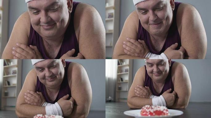 有趣的胖乎乎的男性躺在地板上，用爱看着甜甜圈，意志力