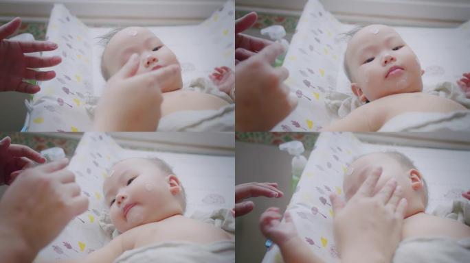 肖像小可爱亚洲新生婴儿婴儿儿童看相机妈妈涂保湿婴儿面霜防止皮肤干燥，母亲护肤婴儿保健概念