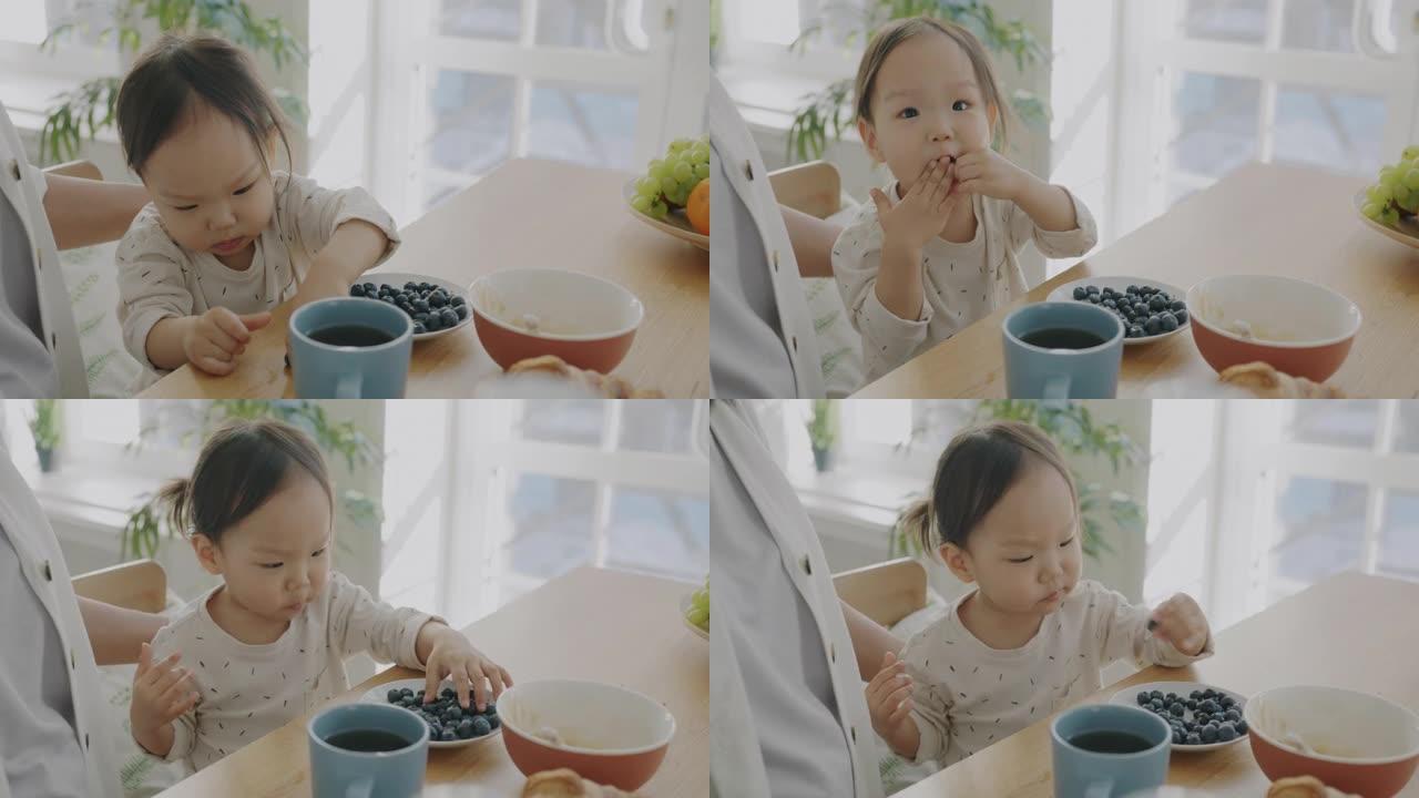 妈妈在家厨房里抚摸孩子表达爱的美丽小女孩吃浆果享受食物的慢动作