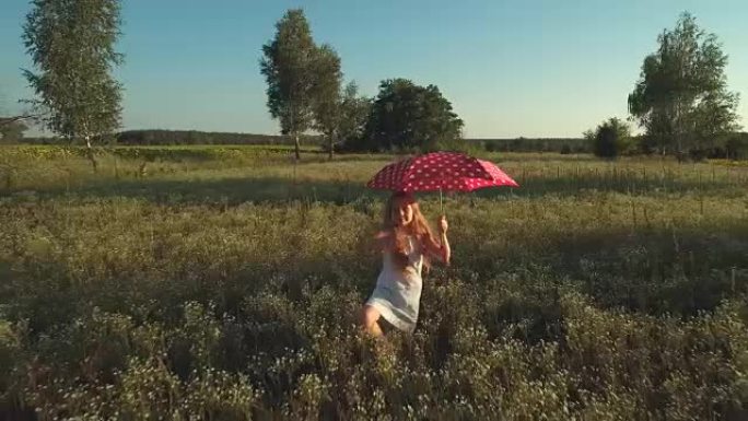 拿着红色雨伞的小女孩挥舞着手，在草地上散步