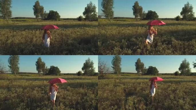 拿着红色雨伞的小女孩挥舞着手，在草地上散步