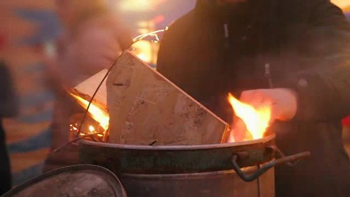 人们用火在大桶前变暖，试图在篝火附近变暖
