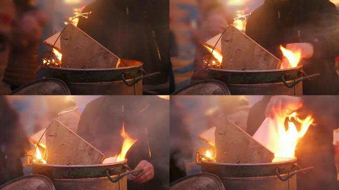 人们用火在大桶前变暖，试图在篝火附近变暖