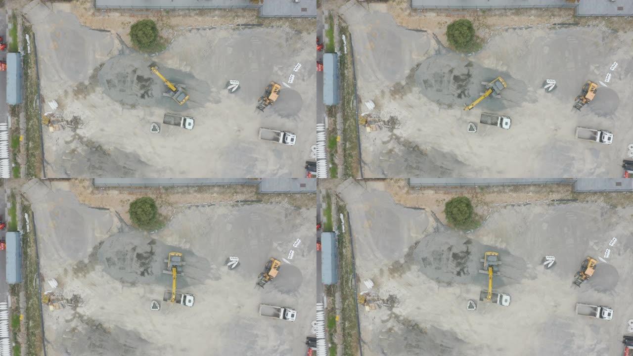 挖掘机在裸露的建筑工地上缓慢地将土壤移动到卡车装载托盘上。