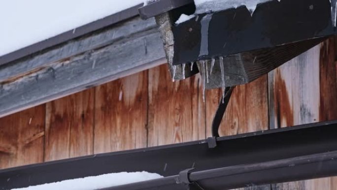 冬季降雪期间在屋顶边缘形成的冰柱和雪团