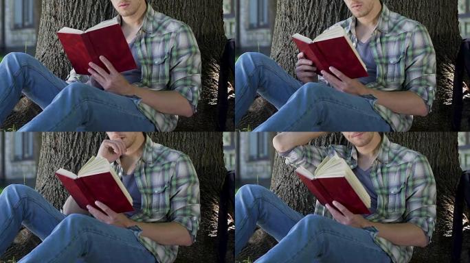 在树下阅读抓着书的家伙，全神贯注于情节，狂热的图书阅读器