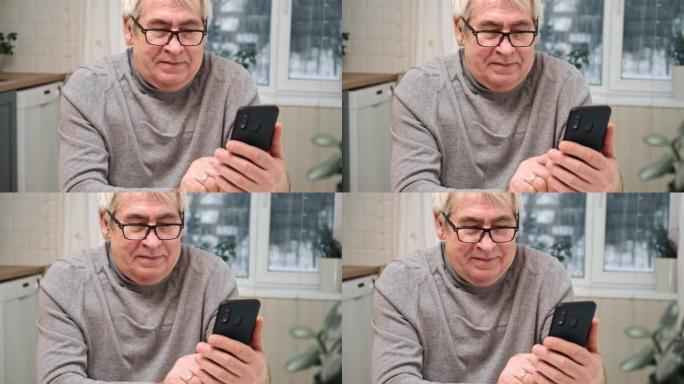 带着微笑的脸看着手机的快乐老人。他看社交网络，看新闻，玩得开心。积极的情感。坐在家里的智能手机的高级