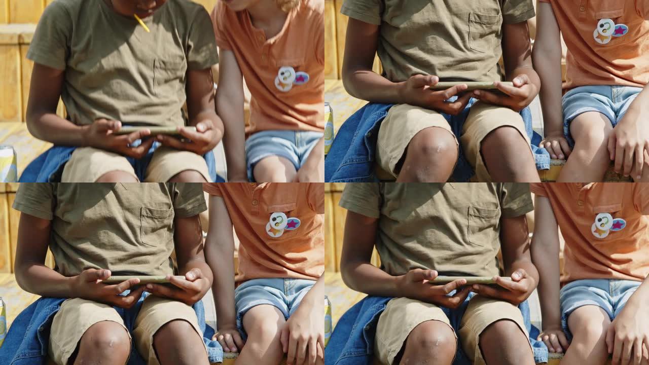 两个不同的孩子在公园的智能手机上玩电子游戏
