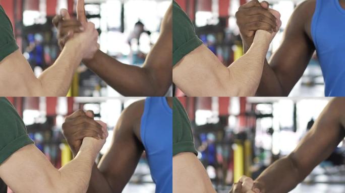 两个男性朋友在健身房握手，强壮男人的肌肉手臂，支持