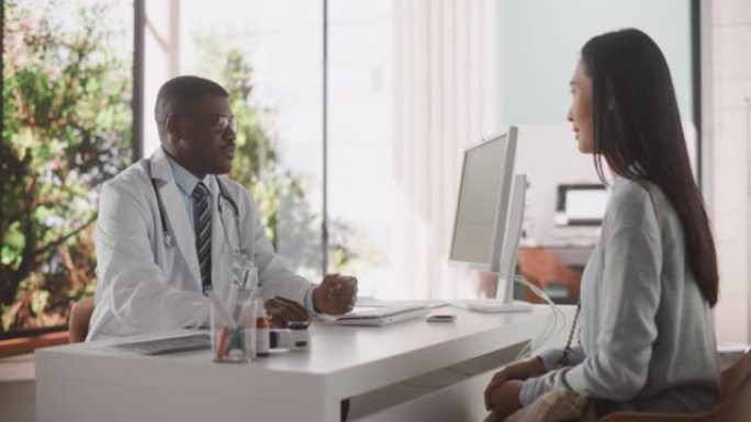 英俊的年轻非洲医生正在与一位多种族的亚洲患者交谈，并在一家健康诊所咨询期间与她交谈。在现代医院工作的