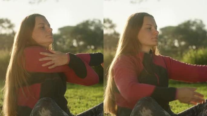 黎明时的一名年轻女子在草坪上的森林里做运动。太阳的光芒落在她的头发上。瑜伽垫。垂直视频社交媒体。