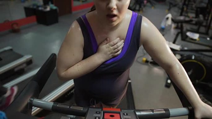女人在跑步机上锻炼错误，呼吸沉重，胸痛