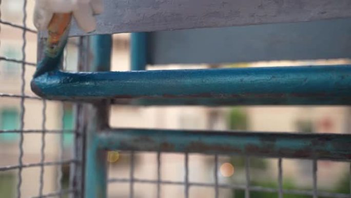 工人用蓝色油漆阳台铁架，修理工用现代高效化学溶液重建旧金属表面，用风化腐蚀和生锈更新钢表面