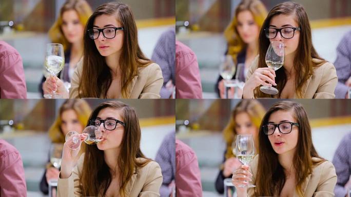 戴眼镜的可爱女孩品尝品尝白葡萄酒