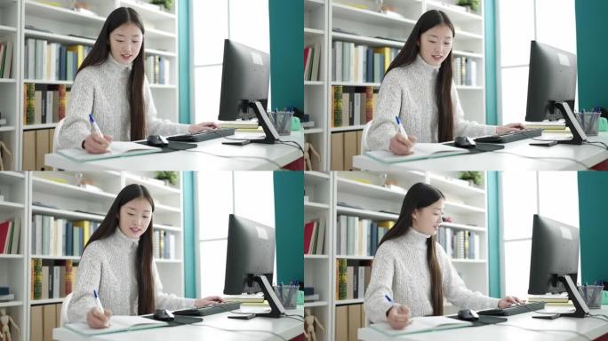 在图书馆大学使用笔记本电脑书写的年轻中国女学生