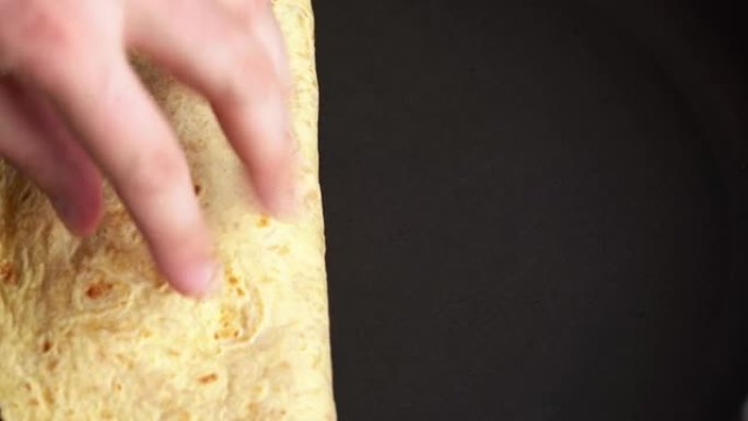 男人在家用煎锅煮玉米饼。厨师用墨西哥大面包玉米饼包装配料