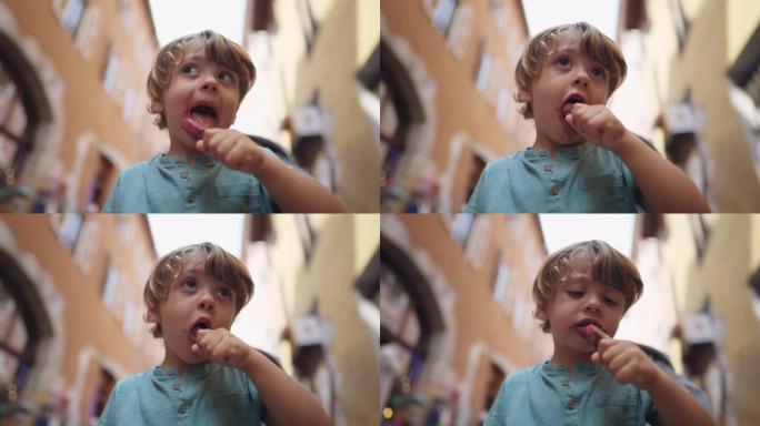 在欧洲大街外面乱七八糟的小男孩在棍子上吃巧克力冰淇淋的肖像。儿童零食甜点