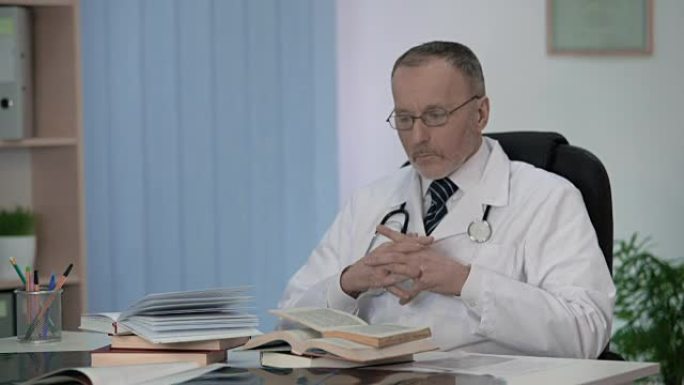 坐在书本堆前的医生为他的研究工作思考主题