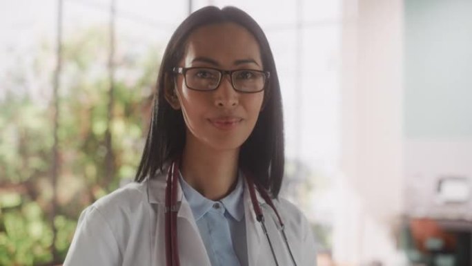 一位经验丰富的亚洲女医生穿着白大褂，在诊所里拿着平板电脑的肖像。年轻的医疗保健专业人员看着镜头轻轻微