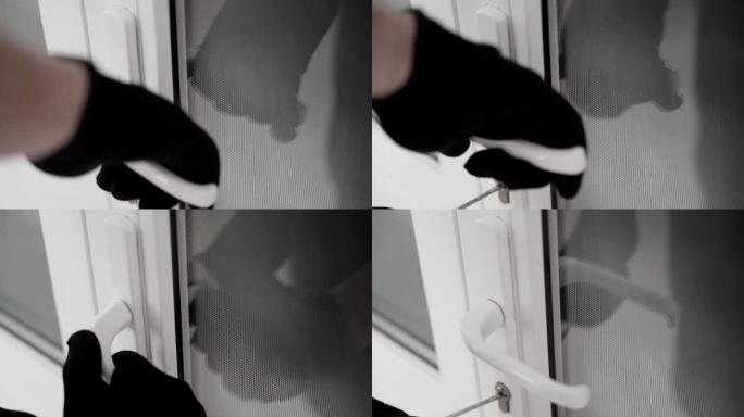 一个戴着黑色手套的人试图用万能钥匙撬开门锁，但没有成功。试图撬开一扇白色塑料门的锁